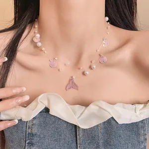 Detailed macro view of a mermaid tail necklace with pearls and shell charms on a model