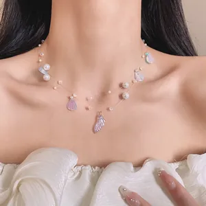 Detail of shimmering pearl and shell fishtail pendant necklace for vacation style