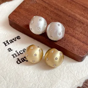 Close-up of silver and gold brushed round stud earrings with star rhinestone inlay