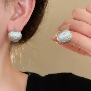 Close-up of brushed silver star stud earrings with sparkling rhinestones