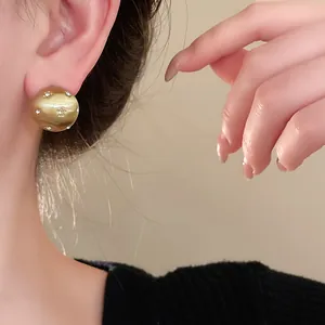 Close-up of a brushed gold star stud earring worn on an ear, showcasing fine details.