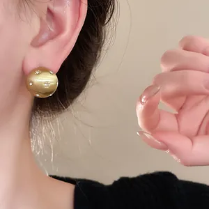 Close-up of a brushed gold hemispherical stud earring with star-shaped rhinestones