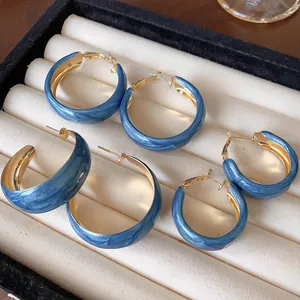 Macro view of three pairs of Klein blue marbled hoop earrings in a jewelry tray.