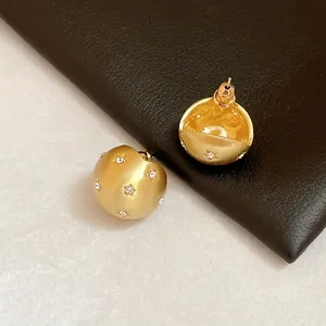 Close-up of gold brushed stud earrings with star-set sparkling rhinestones