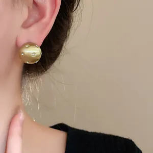 Detailed macro view of gold brushed stud earrings with sparkling star patterns on ear