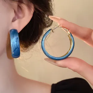 Macro view of Klein blue marbled hoop earrings featuring silver needle and stylish design