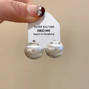 Detailed view of brushed silver round stud earrings with sparkling star rhinestones
