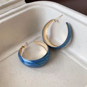 Detailed macro view of Klein blue rendered texture hoop earrings with gold finish