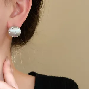 Close-up of minimalist brushed silver round stud earring with star-shaped crystals