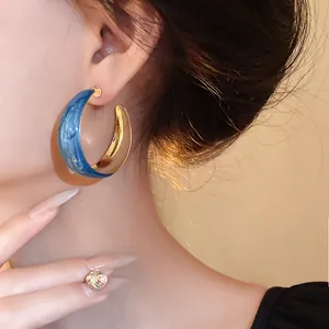 Elegant Klein blue marbled hoop earrings with gold-toned lining, fashion jewelry accessory.