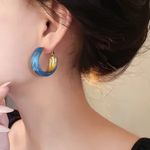 Elegant close-up view of Klein blue marbled hoop earrings with golden inner lining