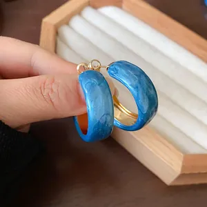 Close-up detail of Klein blue marbled hoop earrings with elegant golden inner lining
