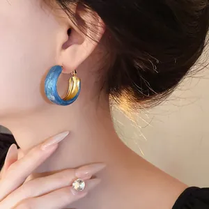 Elegant Klein blue swirl hoop earrings with silver needles shown worn by a model
