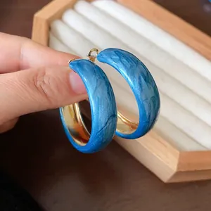Close-up view of Klein blue marble textured hoop earrings with silver needle posts
