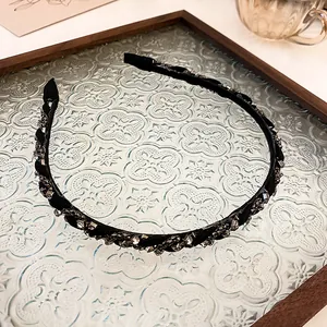 Elegant black twisted headband with sparkling rhinestones on a decorative glass tray.