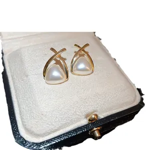 Eleganti orecchini a lobo incrociati in oro con perla bianca triangolare in scatola.