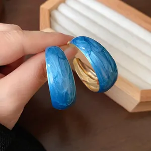 Macro detail view of Klein blue marbled hoop earrings with glossy golden inner finish