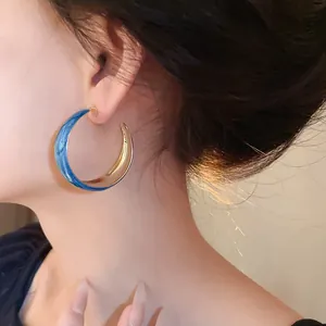 Close-up of a Klein Blue marbled C-shaped hoop earring with a gold inner finish
