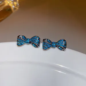 Dettaglio di eleganti orecchini a perno a fiocco con strass blu su ceramica