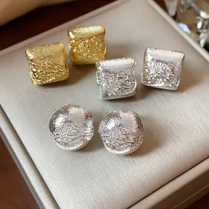 Gros plan détaillé de boucles d'oreilles géométriques dorées et argentées sur un écrin à bijoux
