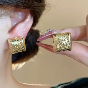 Gros plan détaillé de boucles d'oreilles géométriques plaquées or 18 carats texturées