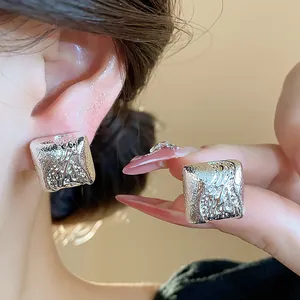 Vue détaillée des clips d'oreilles carrés argentés avec une finition métallique artistique