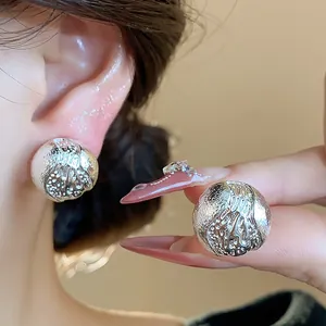 Gros plan détaillé sur des boucles d'oreilles sphériques texturées plaquées or 18k