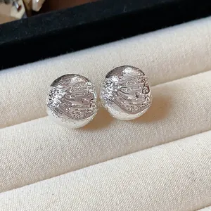 Vue rapprochée de clips d'oreilles sphériques texturés au fini argenté dans un écrin à bijoux
