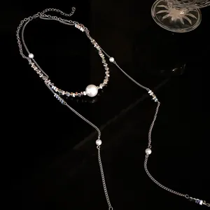 Elegante collana lunga con nappa con perle bianche e perline argentate su fondo nero.