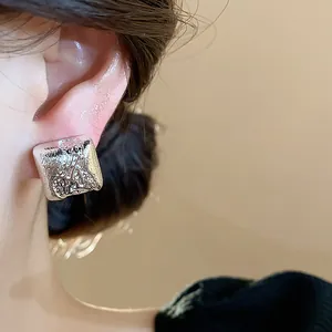 Gros plan détaillé d'un clip d'oreille carré texturé doté d'une élégante finition argentée