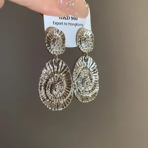 Macro detail view of silver minimalist oval textured earrings with a radiant spiral pattern