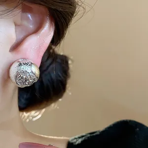 Gros plan d'un clip d'oreille sphérique en argent texturé porté sur une oreille