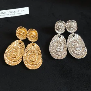 Detailed macro view of gold and silver oval earrings with textured spiral design