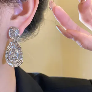 Close-up detail of silver oval textured drop earrings with radiant grooved pattern