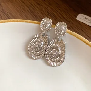 Close-up detail of elegant silver oval drop earrings with a radial shell pattern