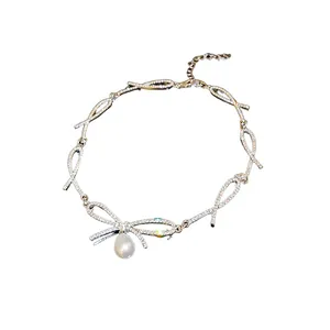 Elegant silver choker necklace featuring a rhinestone bow and drop pearl pendant