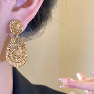 Close-up of model wearing elegant gold-toned textured oval drop earrings jewelry
