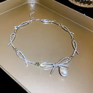 Close-up of elegant rhinestone bow necklace with a white pearl pendant detail