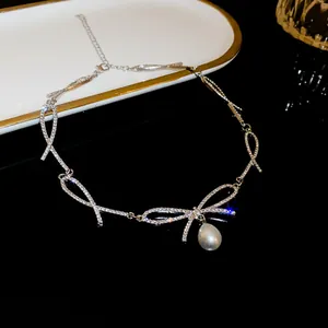 Elegant silver-toned rhinestone bow necklace featuring a lustrous white pearl drop detail.