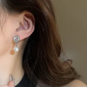 Elegant geometric silver earrings with pavé crystals and pearl drops on a model