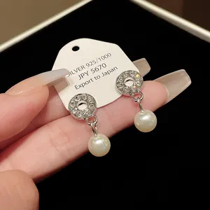 Close-up of elegant silver earrings with sparkling rhinestones and white pearls