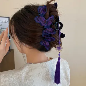 Detailed view of a purple embroidered butterfly hair claw with tassel in a half-updo style