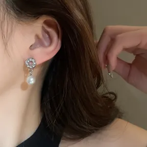 Close-up of French vintage silver earring with sparkling diamonds and white pearl drop