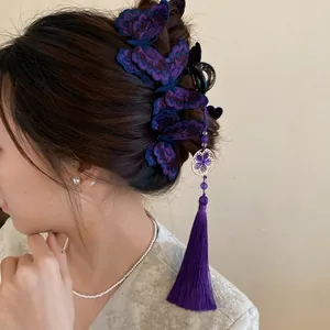 Close-up of purple knitted butterfly hair claw clip with long tassel on dark hair