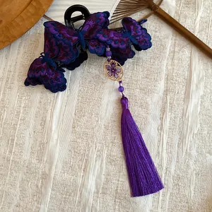Elegant close-up of a purple embroidered butterfly hair claw clip with a long silk tassel