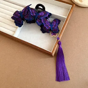 Detailed view of a purple embroidered butterfly hair claw clip with long silk tassel.