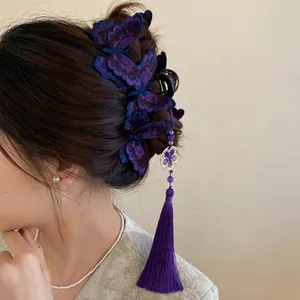 Detailed side view of purple embroidered butterfly hair clip with tassel on dark hair