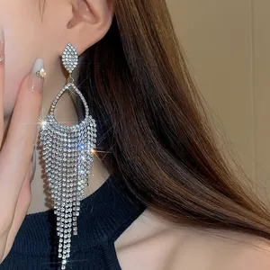 A detailed macro view of sparkling silver rhinestone tassel drop earrings on an ear