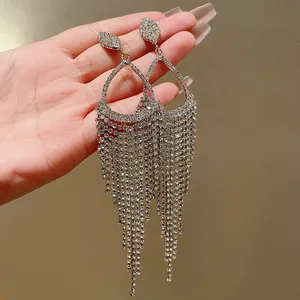 Close-up detail of silver-colored teardrop tassel earrings with sparkling rhinestones