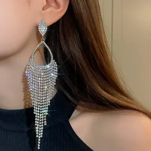 Close-up of elegant rhinestone teardrop tassel earrings worn by a model.